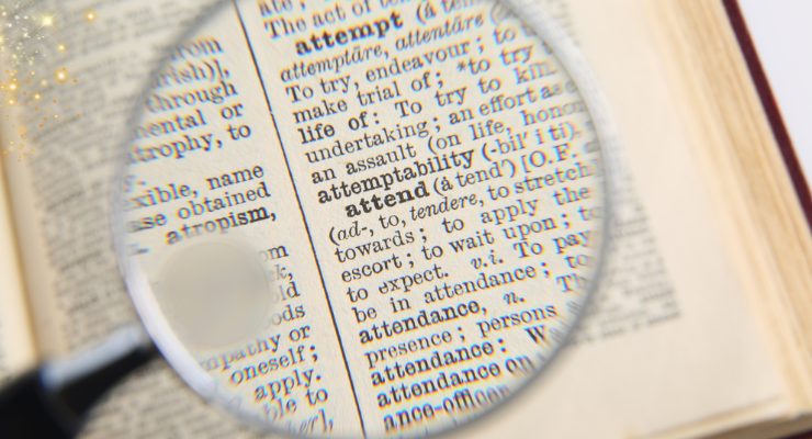 英英辞典の文字を虫眼鏡で拡大して読む様子|語彙力向上や英語学習のイメージ